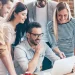 six cheerful young people looking laptop with smile while leaning table office
